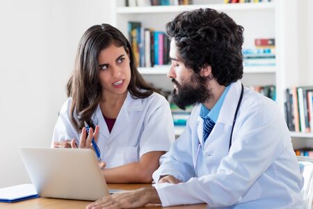 Young arabic female doctor talking with male doctor about patientの写真素材