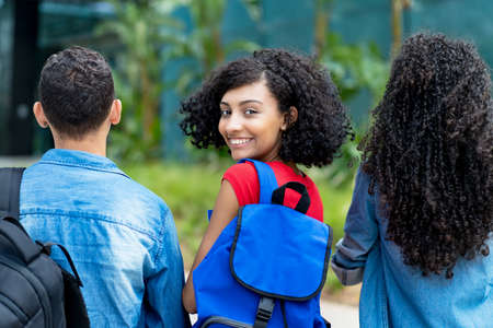 Laughing hispanic female student with backpack and group of friendsの写真素材