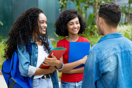Hispanic female students talking with friend after classの写真素材