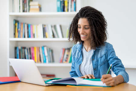 Learning latin female student with curly hair at computerの写真素材