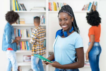 Beautiful african american female student with dreadlocks and group of young adultsの写真素材