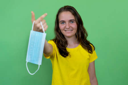 Laughing german female young adult presenting face mask as protection against corona virusの写真素材
