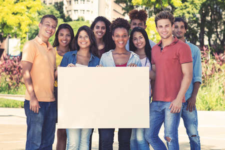 Group of multi ethnic funny laughing friends holding blank bannerの写真素材