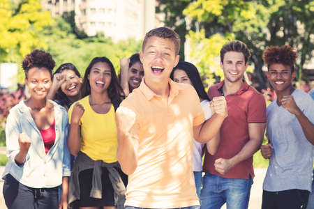 Young male student with group of cheering young adultsの写真素材