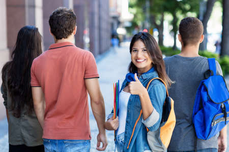 Successful spanish female student with group of young adults outdoor in cityの写真素材