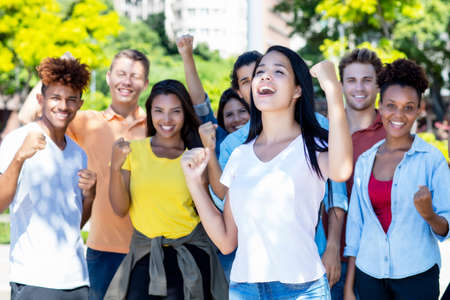 Successful south american female student with group of cheering young adultsの写真素材