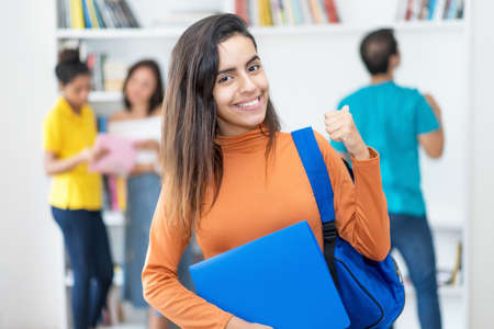 Laughing Colombian female student, with group of young adults at classroom