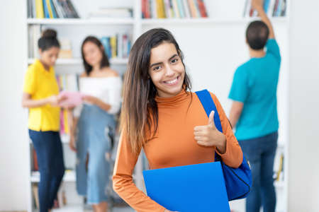 Successful Colombian female student, with group of young adults at classroomの写真素材