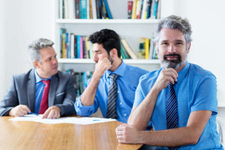 Handsome elderly businessman with beard and motivated team at officeの写真素材