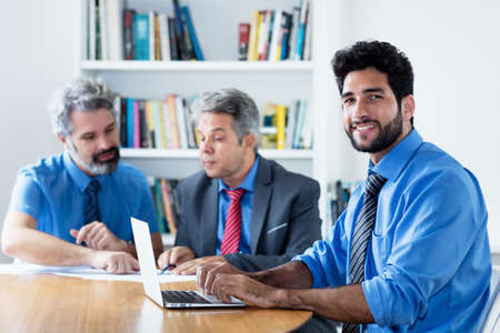 Handsome hipster businessman with beard and older colleagues at the officeの写真素材