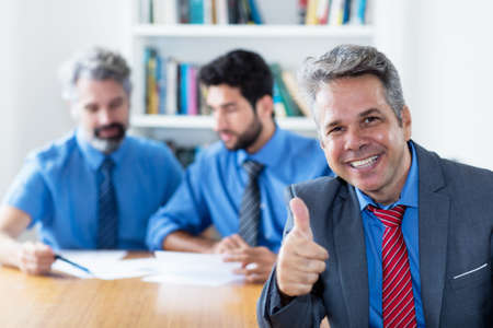 Successful elderly businessman with motivated team at officeの写真素材