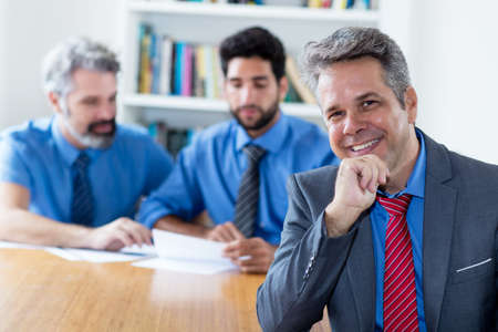 Handsome elderly businessman with motivated team at officeの写真素材
