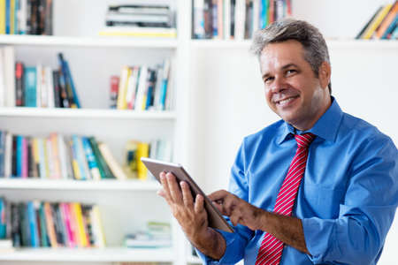 Laughing businessman reading business news online with tablet computerの写真素材