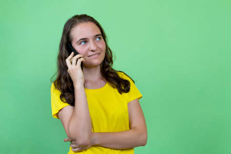 Pretty german young adult woman with brunette hair talking at mobile phoneの写真素材