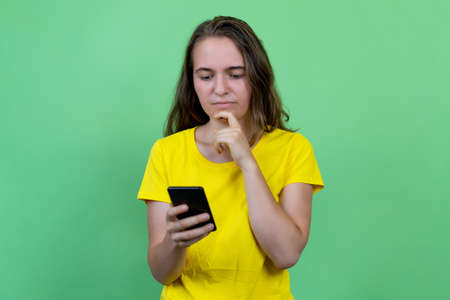 Young german young adult woman with brunette hair sending message with mobile phoneの写真素材