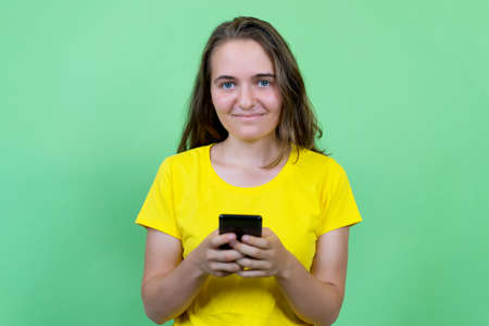 Laughing german young adult woman with brunette hair sending message with mobile phoneの写真素材