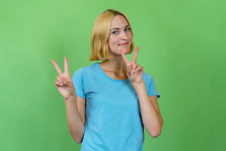 Young woman with colored blond hair showing victory gestureの写真素材
