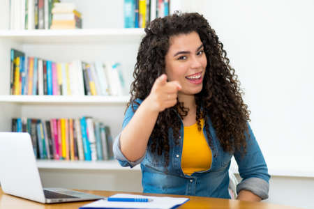Laughing hispanic woman loves working indoors at home at computer during the pandemicの写真素材