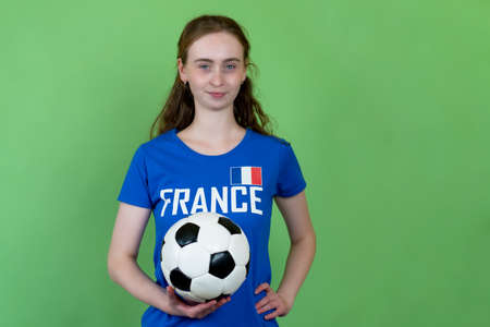 French female soccer supporter with ball isolated on green backgroundの写真素材