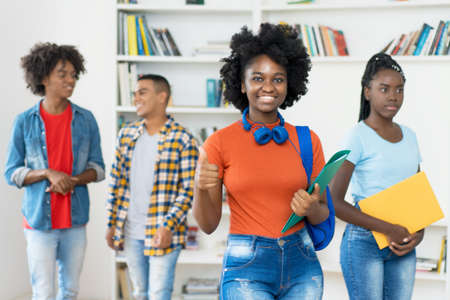 Successful afro american female student with group of black young adults at library of universityの写真素材