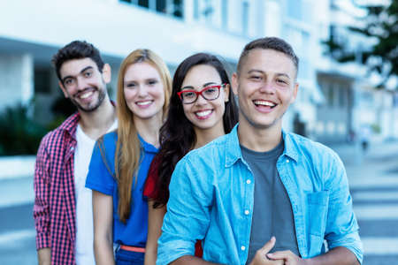 Laughing german young adult man with group of friends in lineの写真素材