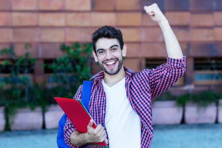 Happy spanish male student cheering about graduation outdoor in cityの写真素材