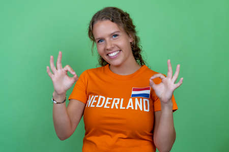 Laughing female soccer fan from Netherlands isolated on green backgroundの写真素材