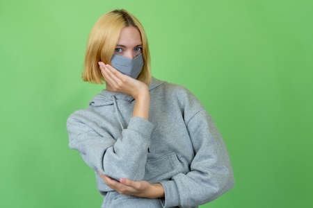 Woman wearing protective mask as protection against coronavirus pandemic covid-19 isolated on green...