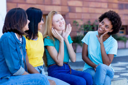Group of multi ethnic girls talking and joking outdoor in summer in cityの写真素材
