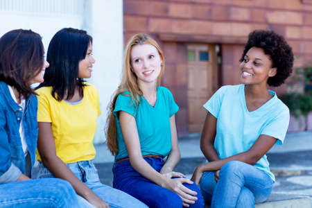Group of young adult women talking about boyfriends outdoor in summer in cityの写真素材