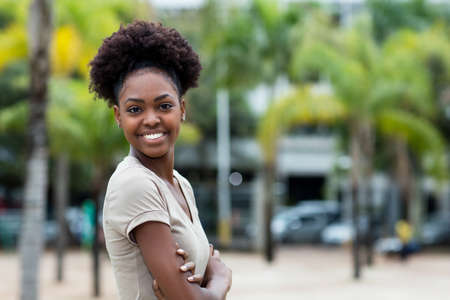 Happy laughing caribbean woman with afro hair and copy space outdoor in summer in cityの写真素材