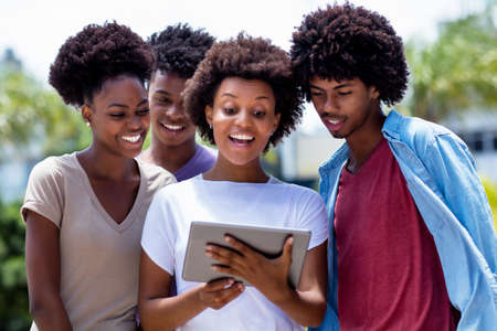 Happy african american young adults streaming movie with digital tablet outdoor in summer in cityの写真素材