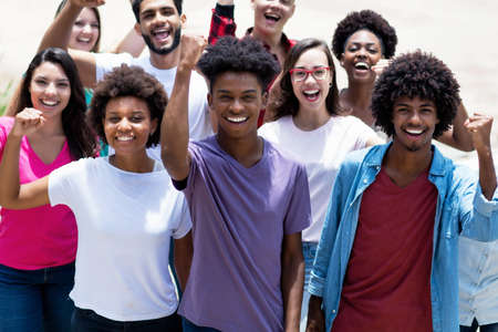 Successful cheering latin and hispanic and african american and caucasian young adults outdoor in summer in cityの写真素材