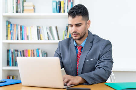 Video call of mexican businessman at computer indoors at officeの写真素材