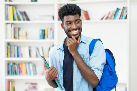Handsome young african american male student with beard at library of universityの写真素材