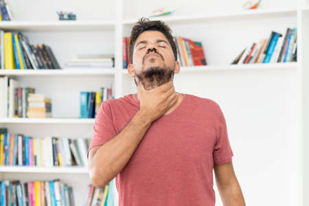 Mature adult mexican man with throat pain indoors at homeの写真素材