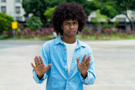 African american male young adult gesturing stop and distance outdoor in summer in cityの写真素材