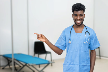 Pointing african male nurse at vaccination station is ready for vacinating patients against coronavirus infectionの写真素材