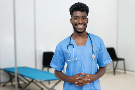 Laughing african male nurse at vaccination station is ready for vacinating patients against infectionの写真素材