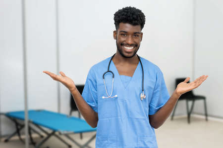 Friendly african male nurse at vaccination station is ready for vacinating patients against infectionの写真素材