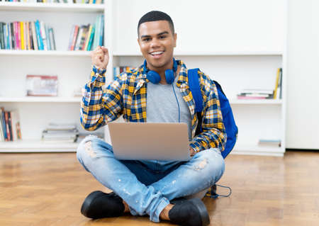 Hispanic male student with braces shopping online at computer indoors at homeの写真素材