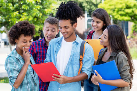 Laughing young hispanic male student talking with multi ethnic young adultsの写真素材