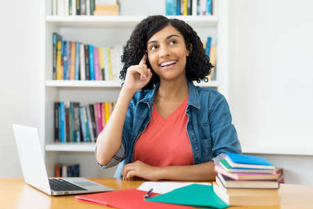 Creative female student - laughing peruvian young adult woman at desk at classroomの写真素材