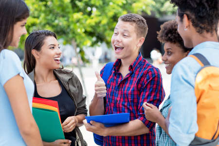 Handsome german exchange student talking with multi ethnic young adults outdoor in summer in cityの写真素材