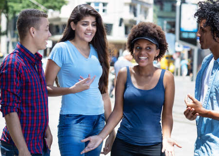 Caucasian and latin and african amerincan and hispanic young adults talking and hanging out outdoor in summer in cityの写真素材