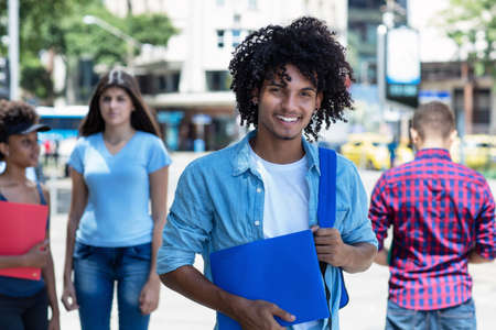 Laughing mexican male student with other young adults outdoor in summer in cityの写真素材