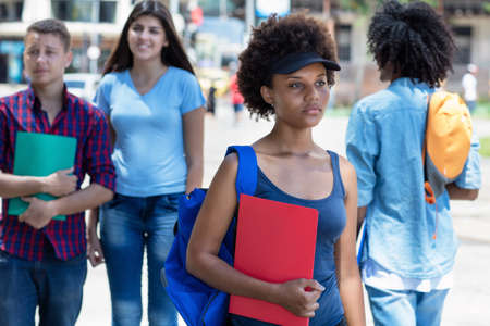 Serious african american female student walking to university outdoor in summer in cityの写真素材