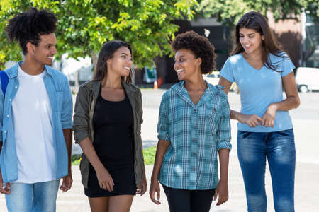 Male and female students and young adults talking and walking outdoor in summer in cityの写真素材