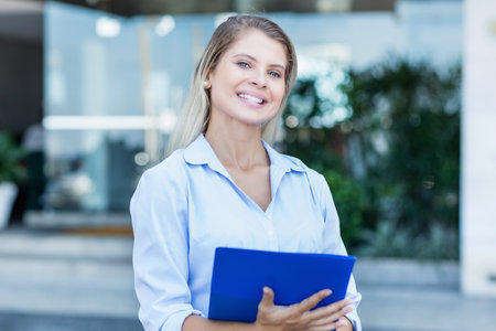 Beautiful blond businesswoman looking at camera outdoor in city in summerの写真素材