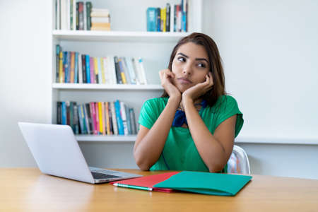 Lonely and sad latin female student thinking about the life at homeの写真素材